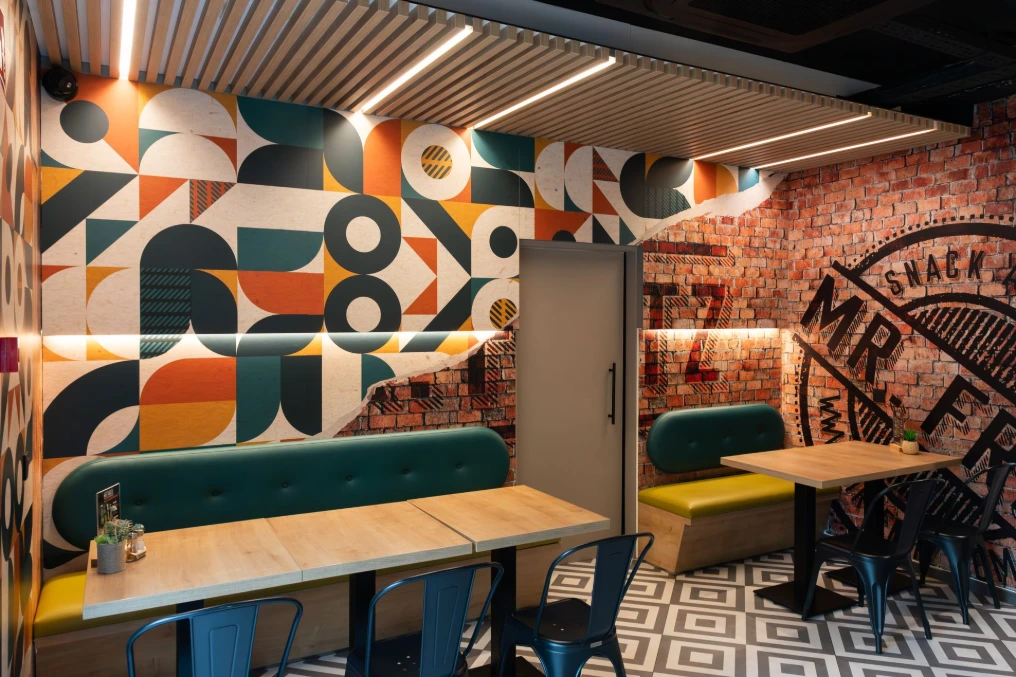 Salle avec banquettes bleu canard, tables en bois clair et fresque géométrique — Mr Fritz Fontaine