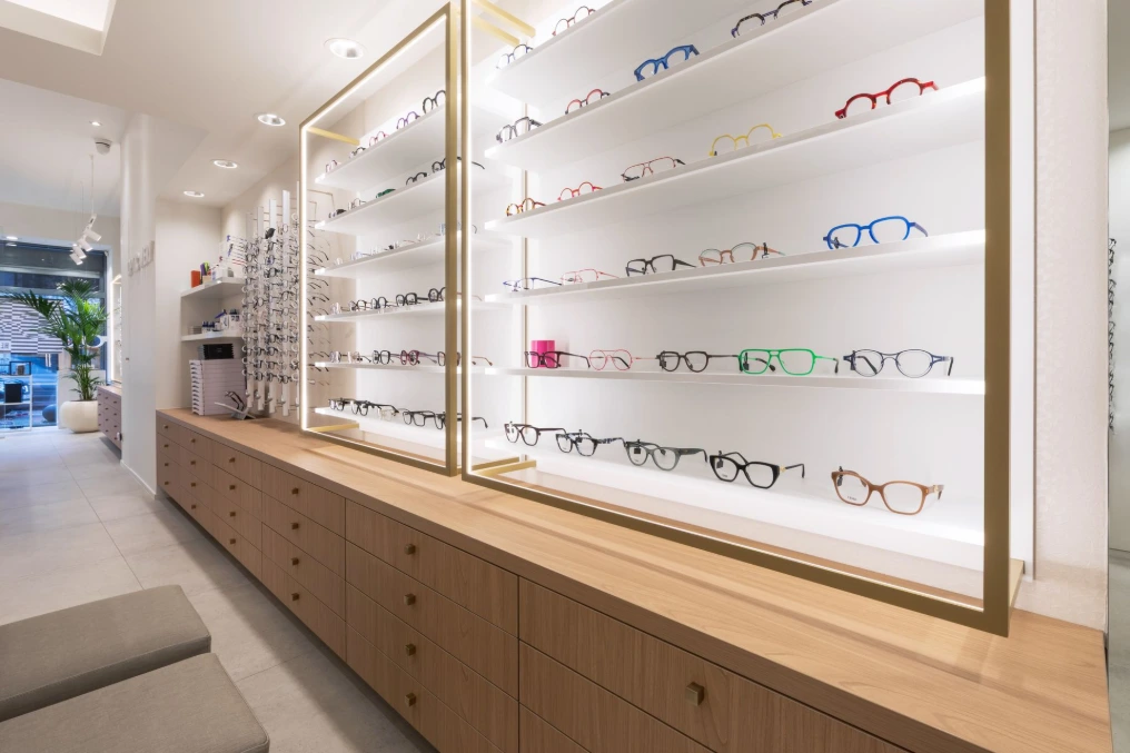 Longue vitrine rétroéclairée de montures au-dessus d'un meuble bas en bois — Optic Wery