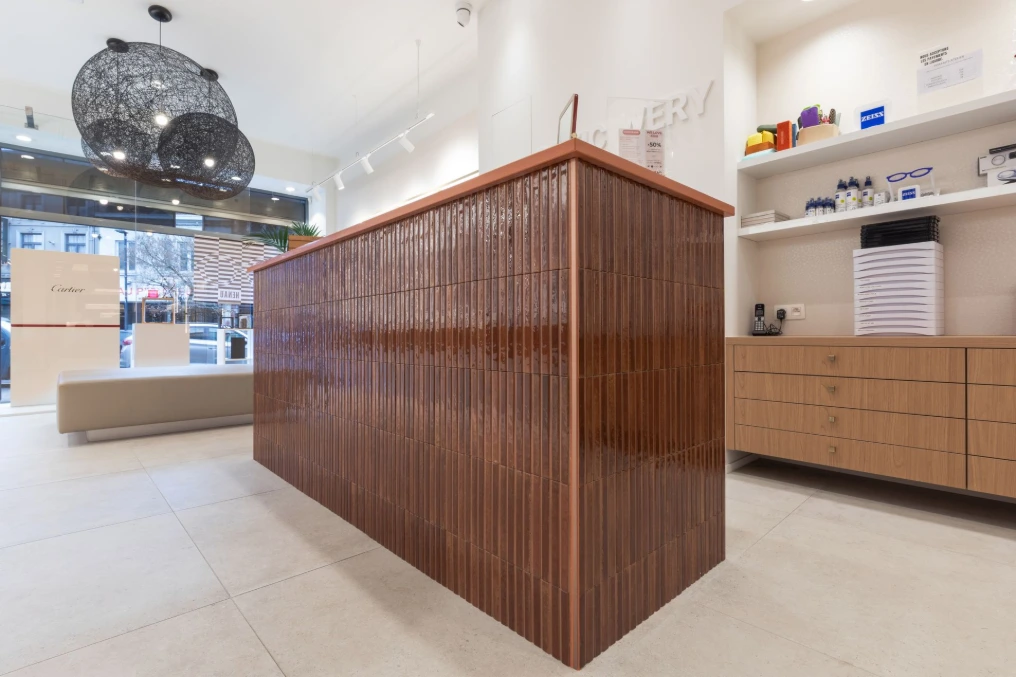 Comptoir en lattes de bois foncé face à la vitrine — Optic Wery