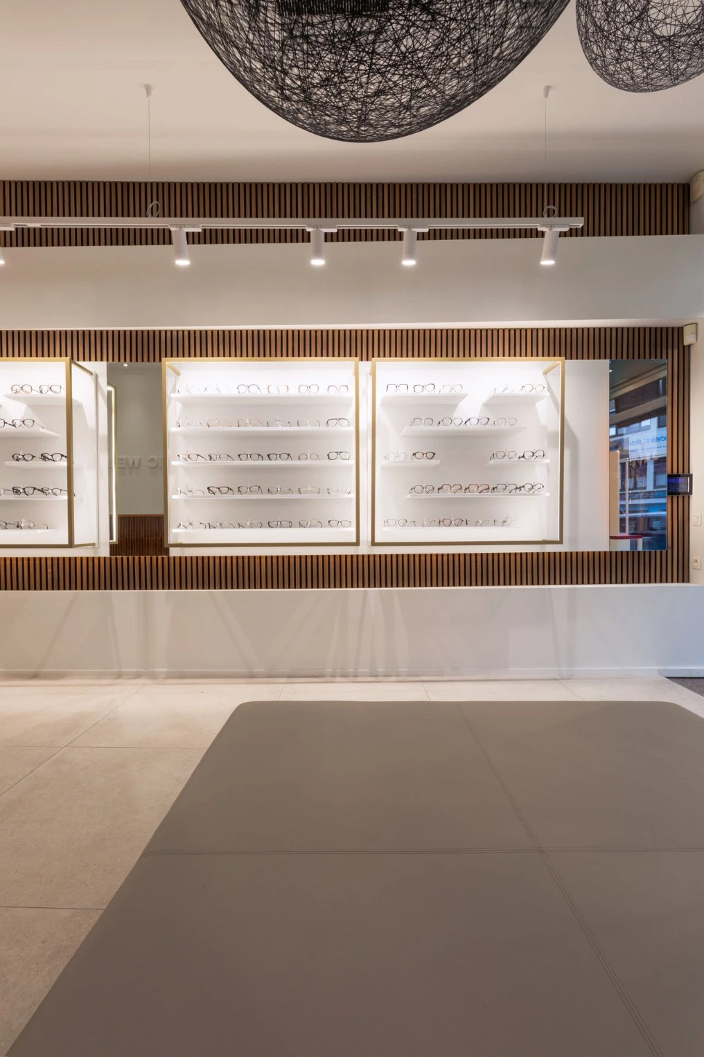 Vitrines de montures rétroéclairées sur mur blanc — Optic Wery