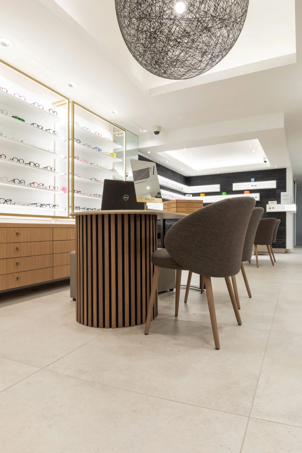 Espace d'essayage : table et fauteuils devant les présentoirs à lunettes — Optic Wery