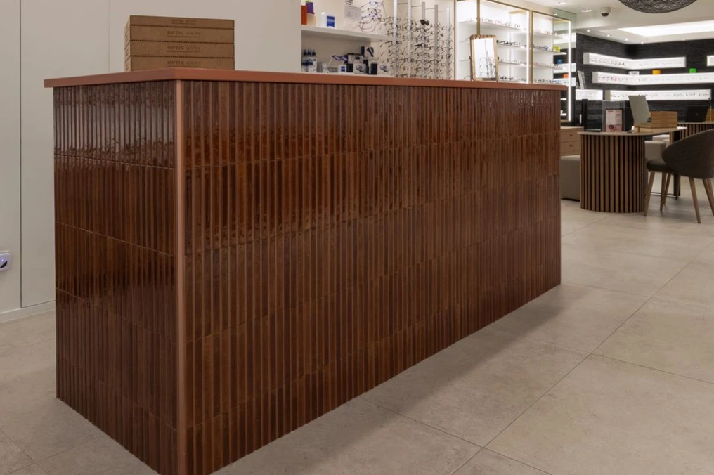 Comptoir de vente en lattes de bois foncé sur sol clair — Optic Wery
