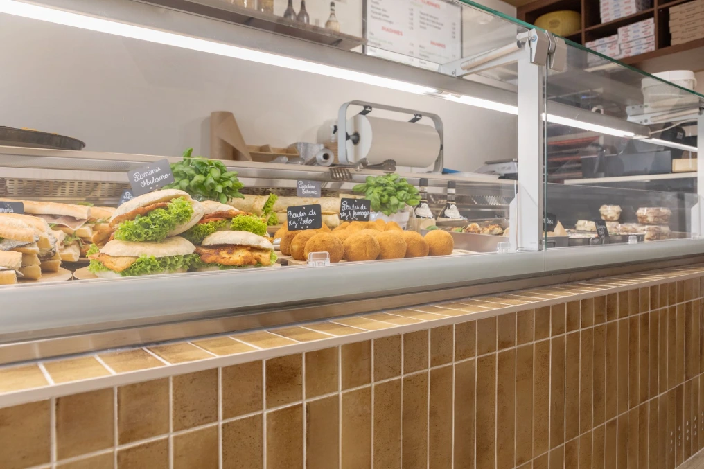 Vitrine réfrigérée garnie de préparations traiteur, habillage en carrelage — Pizzeria Traiteur Titanic