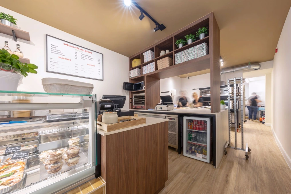 Zone de caisse : comptoir en bois clair, vitrine réfrigérée et cave à boissons — Pizzeria Traiteur Titanic