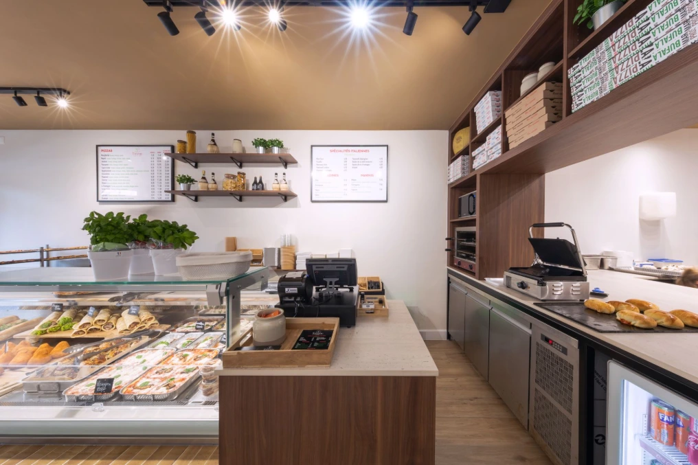 Arrière-comptoir avec plan de travail, étagères et matériel de préparation — Pizzeria Traiteur Titanic