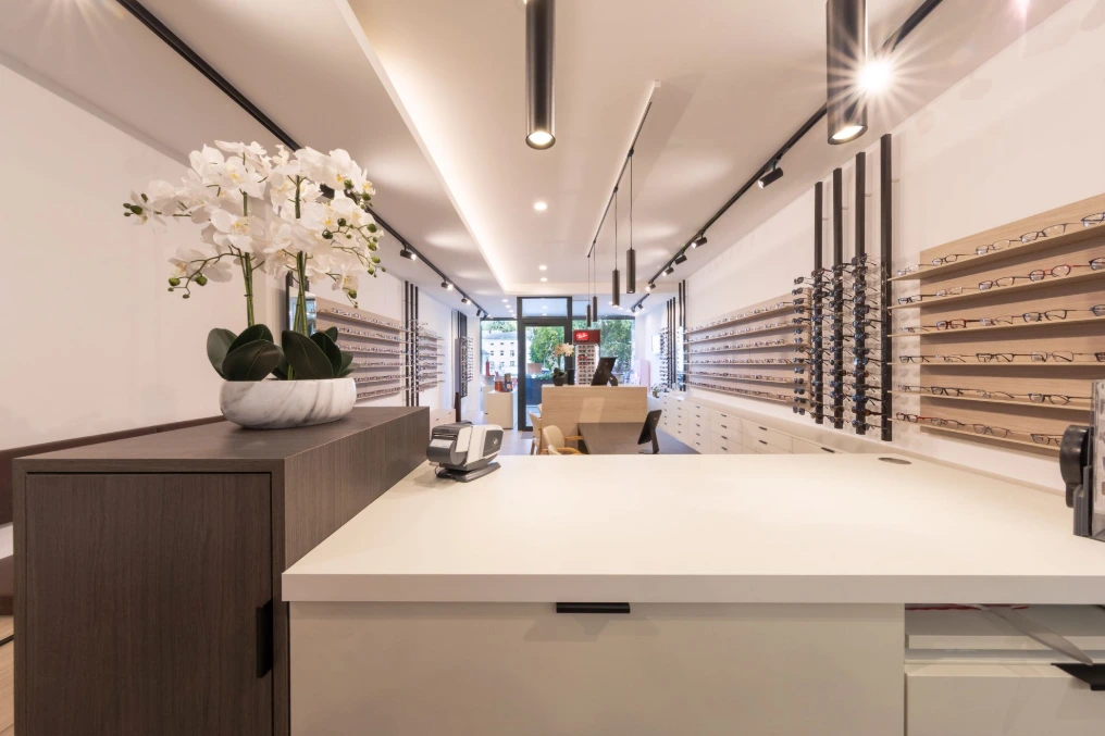 Comptoir en pierre claire et vue vers l'entrée du magasin — Optique Lecapitaine