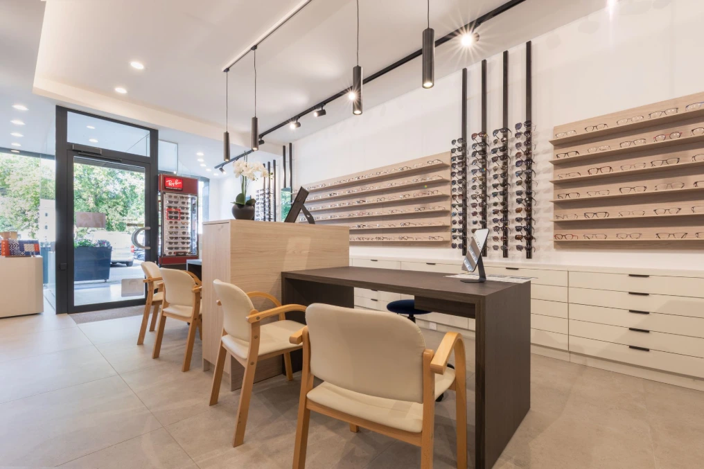 Coin conseil près de la vitrine : table ronde et fauteuils en bois — Optique Lecapitaine