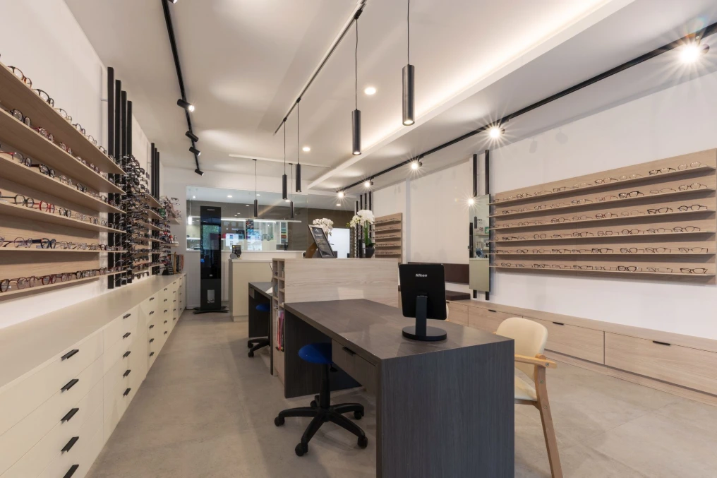 Table d'essayage avec miroir face aux présentoirs muraux — Optique Lecapitaine