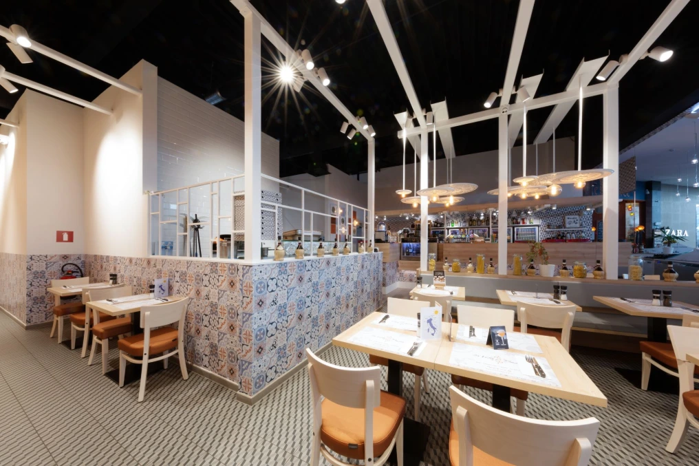 Salle du restaurant : tables claires, banquettes et structure en pergola blanche — La Vita e Bella - Grands Prés