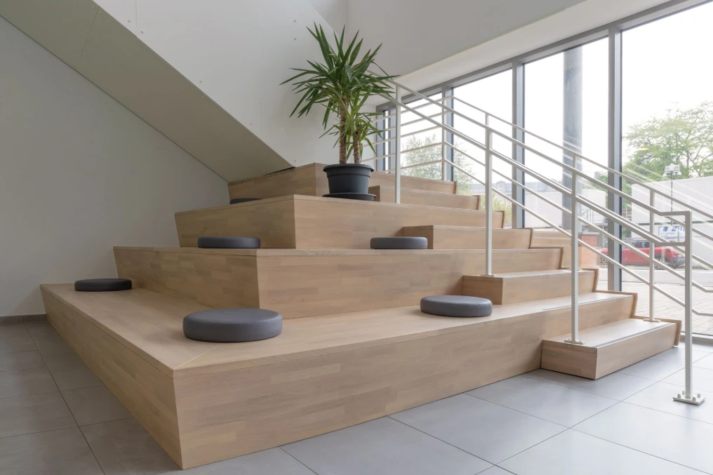 Escalier-gradin en bois clair devant la baie vitrée du hall — Service Public de Wallonie