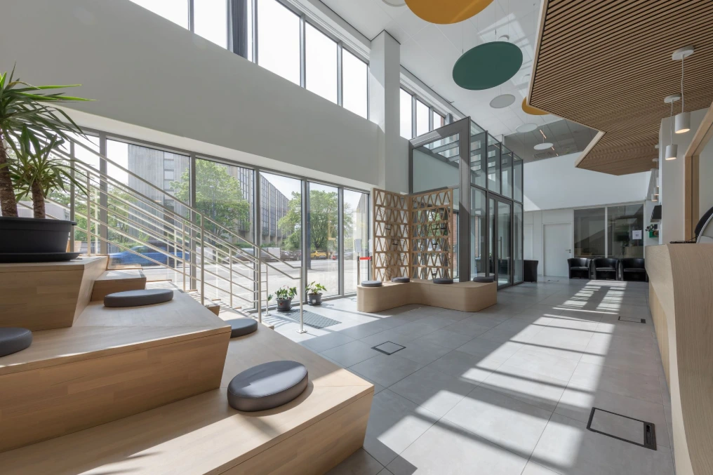 Hall vitré avec gradins, plafonds acoustiques suspendus et plantes — Service Public de Wallonie