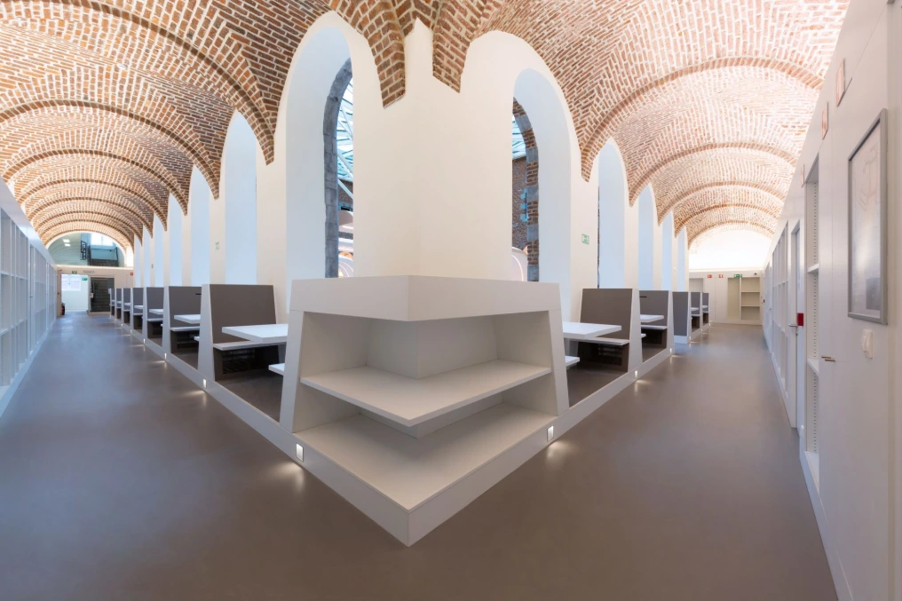 Table de travail blanche entre les alcôves voûtées — Bibliothèque U-Mons