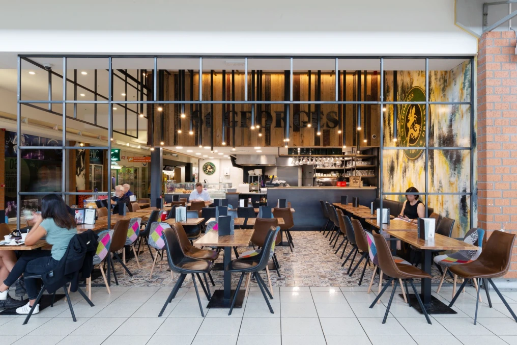 Salle du restaurant : tables en bois, fauteuils et verrière atelier — St Georges