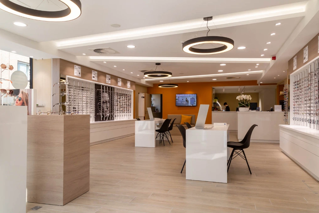 Espace de vente avec suspensions annulaires et coin essayage orange — Optique Bernard
