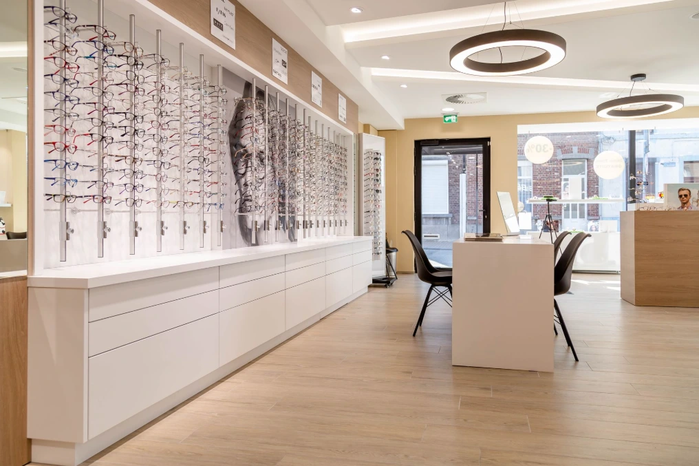 Longue vitrine de montures rétroéclairée et visuel mural — Optique Bernard