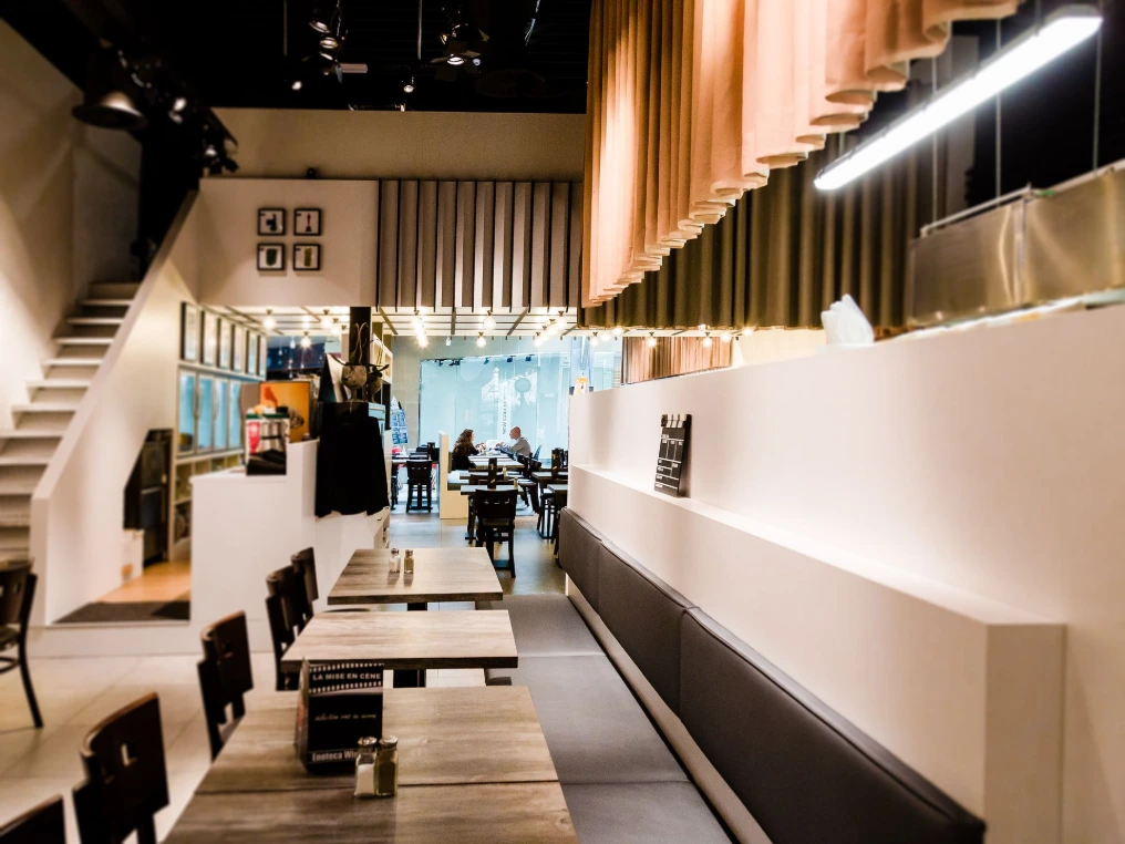 Comptoir blanc en longueur, banquettes et tables noires — La Mise en Cène - Mons