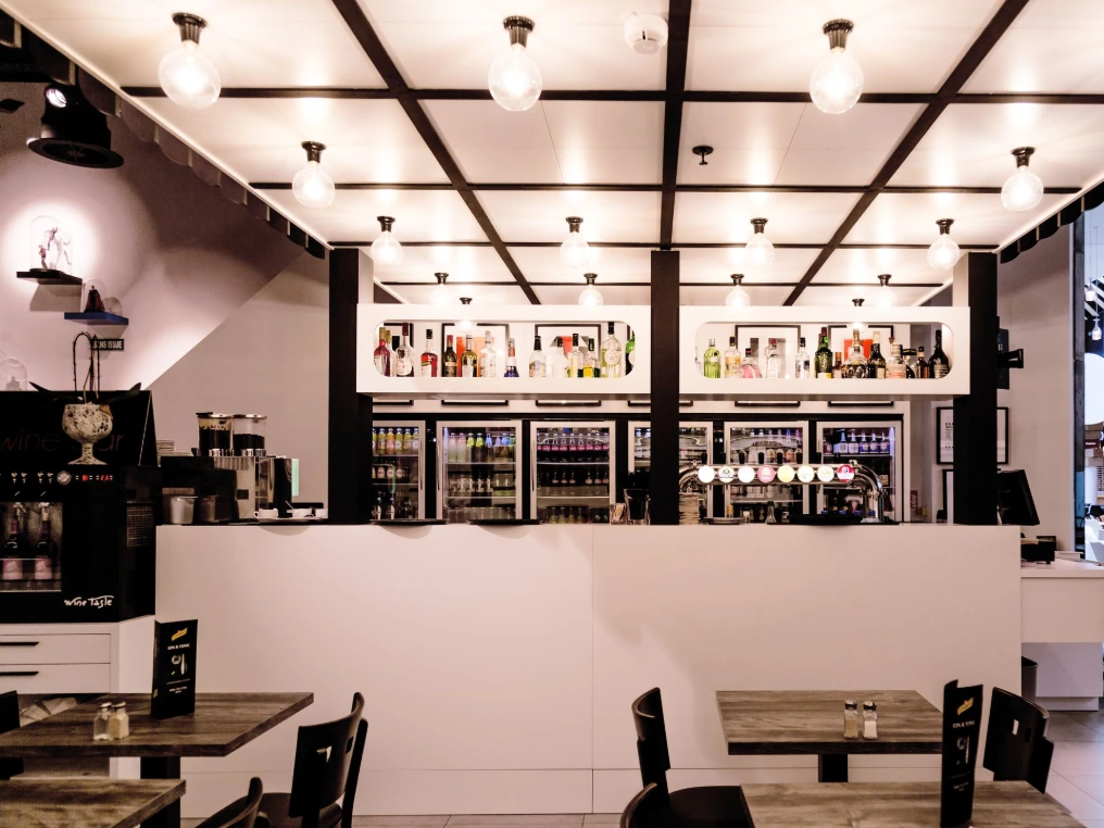 Bar avec machines à café, vitrines et tables hautes — La Mise en Cène - Mons