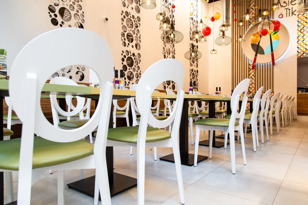 Tables dressées et chaises blanches devant le mur à motifs — Asie a tik - Bastions