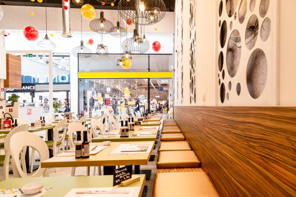 Salle du restaurant avec banquettes, tables et cloison en bois perforé — Asie a tik - Bastions