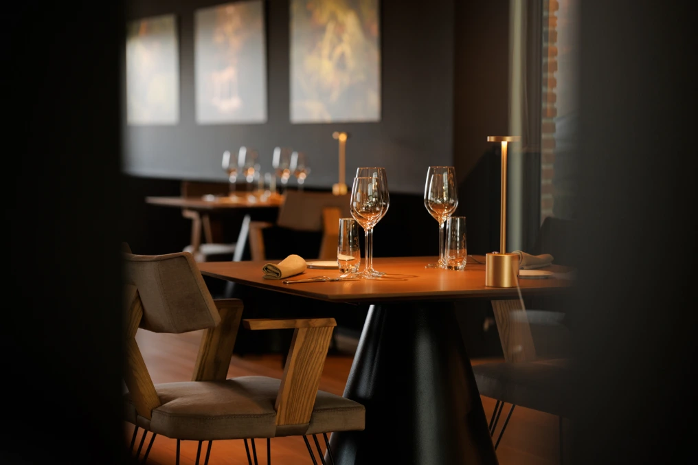 Table dressée avec fauteuils en cuir clair et éclairage tamisé — Le Bouchon et l'Assiette