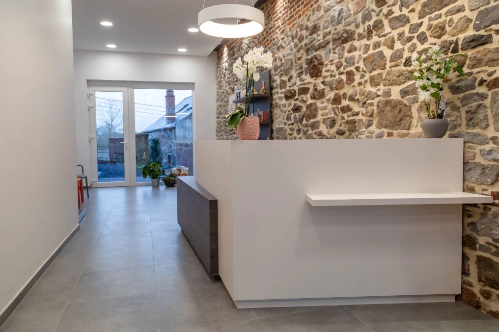 Salle d'attente avec mur en pierre, banquette et comptoir bas — Centre vétérinaire Optimavet