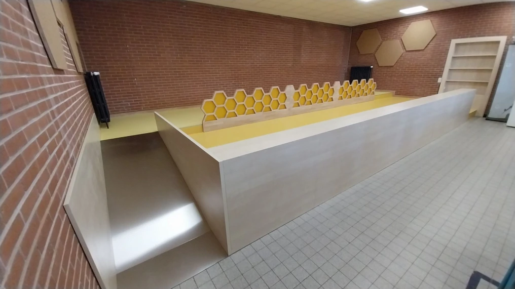 Estrade avec plan en bois clair et rambarde jaune — École maternelle Morlanwelz
