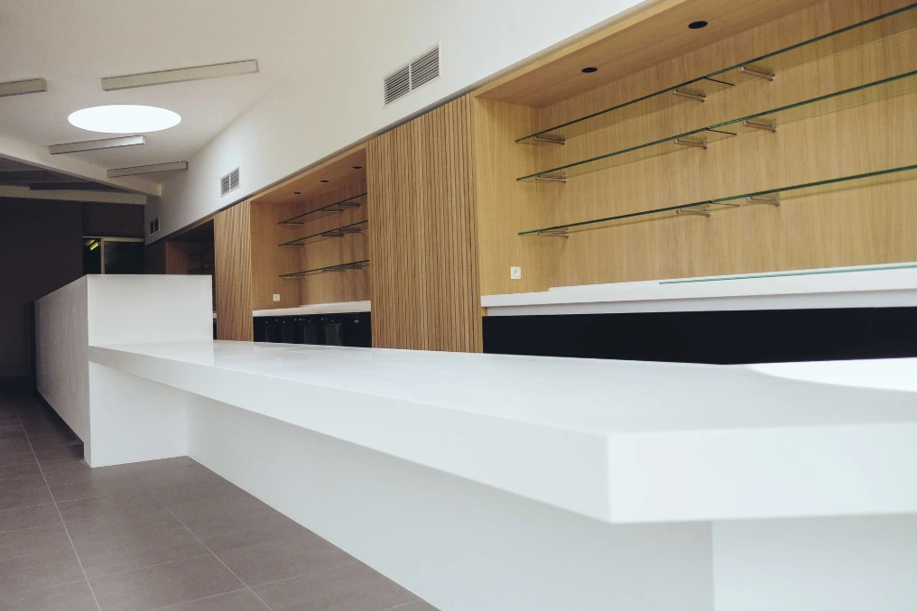 Bar de la salle commune : plan blanc et rangements muraux en bois — Maison de repos Les Buissonnets
