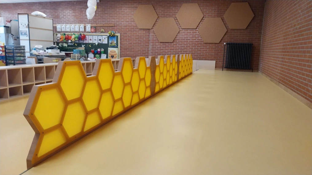 Estrade et rambarde jaune en nids d'abeilles le long de la salle — École maternelle Morlanwelz