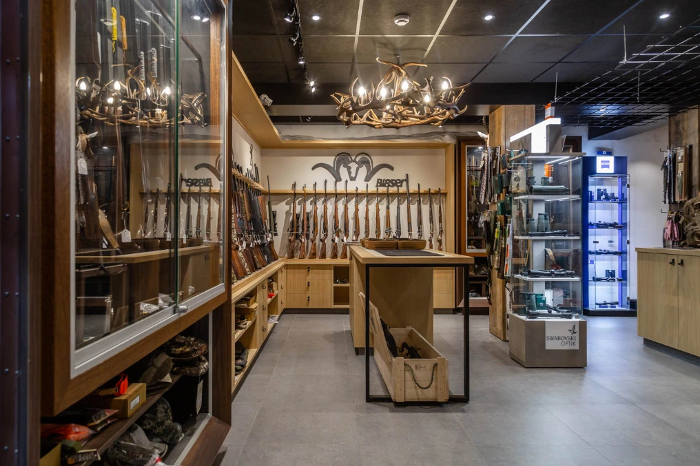 Longue vitrine et présentoirs centraux sous les lustres — Armurerie Supershooting