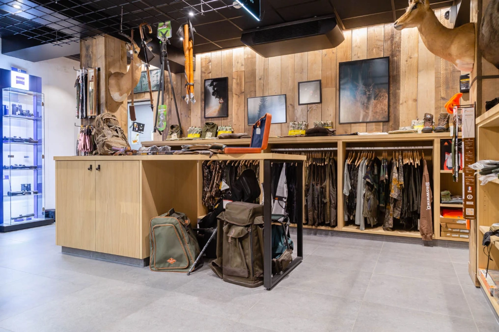 Espace de vente avec rayonnages en bois, vitrines et équipement de chasse — Armurerie Supershooting