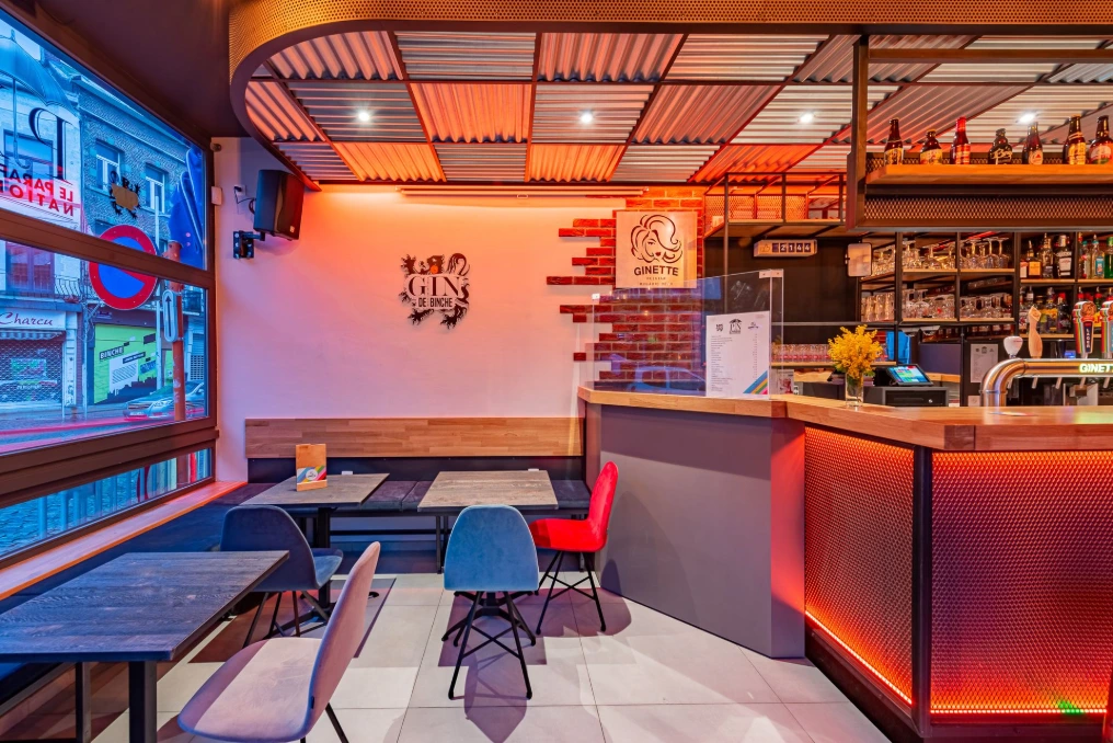 Espace lounge avec écrans, banquettes bleues et bar — Café « Le Parapluie National »