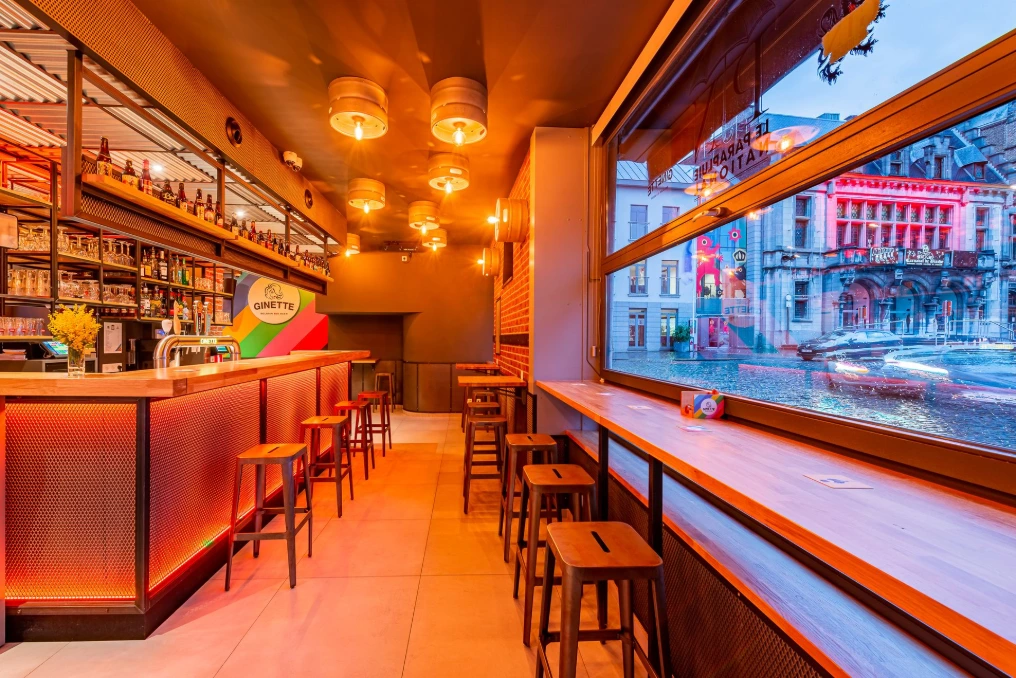 Bar en longueur avec tabourets et suspensions face aux baies vitrées — Café « Le Parapluie National »