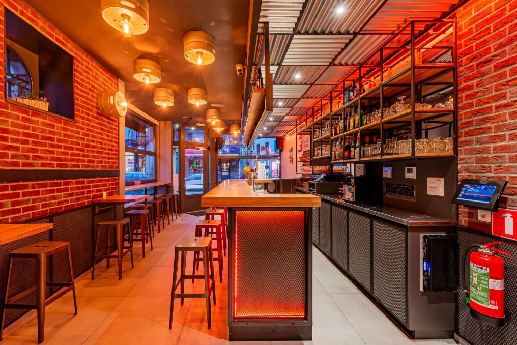 Vue d'ensemble : comptoir central, banquettes et mur en briques — Café « Le Parapluie National »