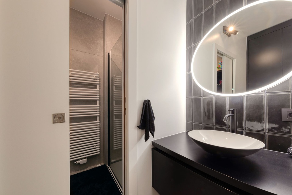 Salle de bains avec douche à l'italienne, miroir rond et carrelage gris — Modifications d'une cuisine et rénovation d'une salle-de-douche