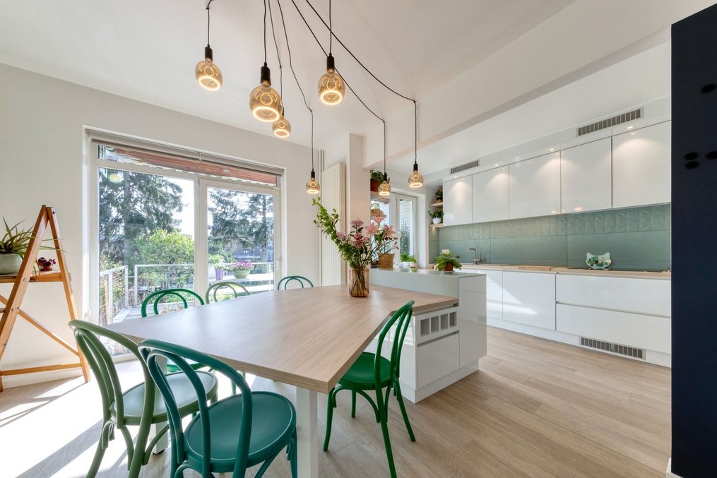 Cuisine blanche avec table en bois, chaises vertes et suspensions — Modifications d'une cuisine et rénovation d'une salle-de-douche
