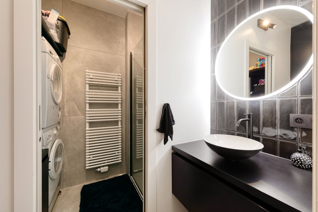 Salle de bains : meuble vasque noir, miroir rond rétroéclairé et sèche-serviettes — Modifications d'une cuisine et rénovation d'une salle-de-douche