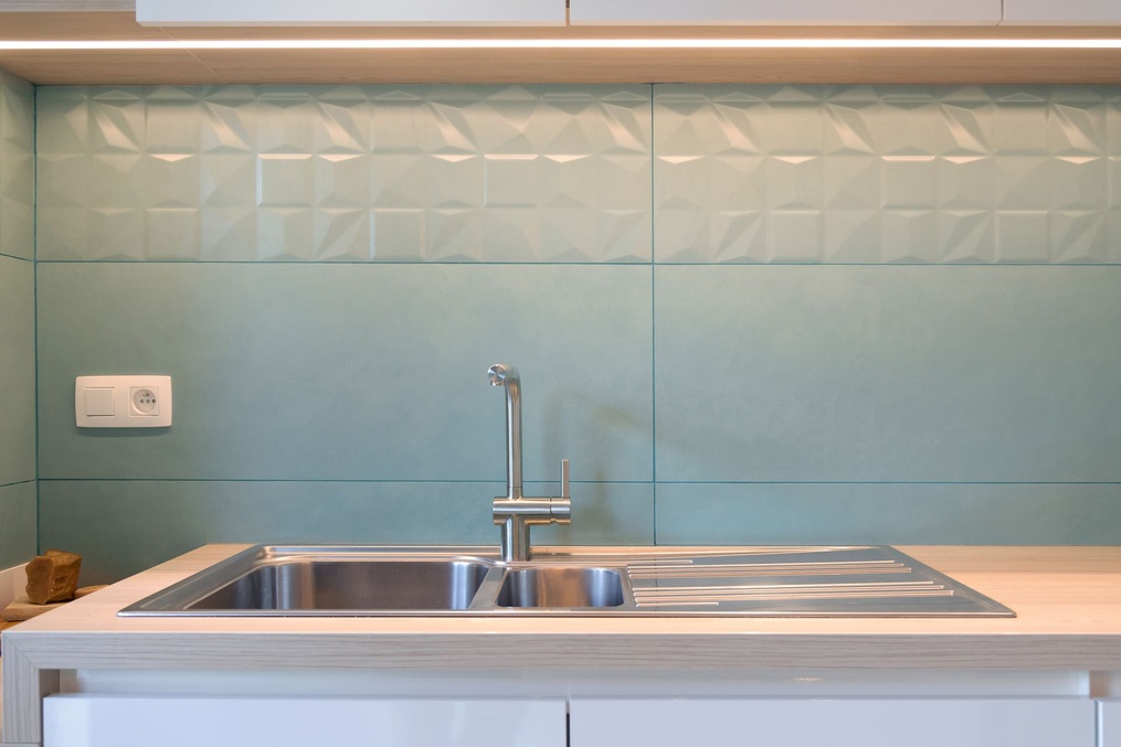 Évier en inox sous la crédence en carrelage vert d'eau — Modifications d'une cuisine et rénovation d'une salle-de-douche