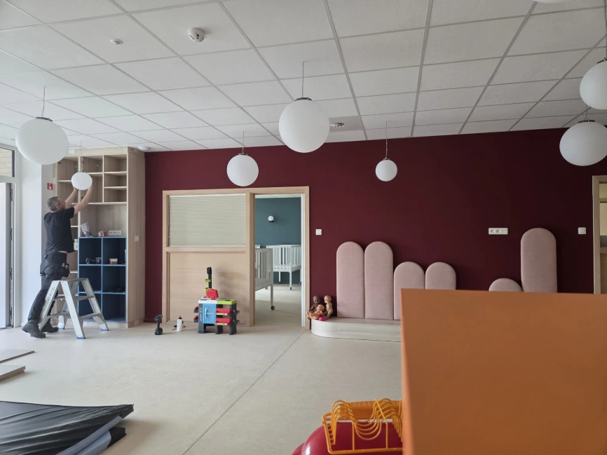 Grande salle avec mur bordeaux, maisonnettes et casiers de rangement — Crèche « Les bulles d'O »